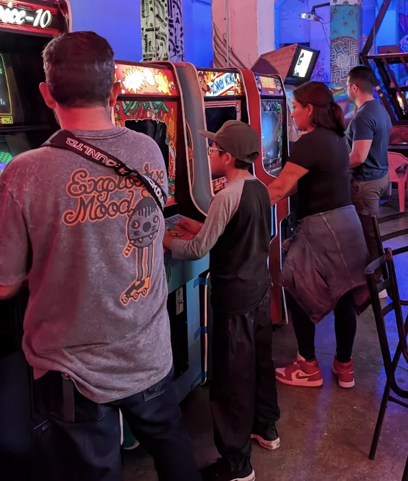 Fila de máquinas arcade con visitantes